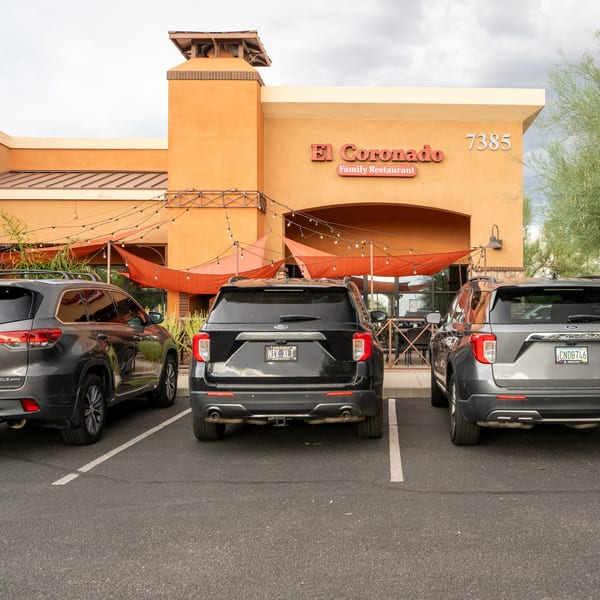El Coronado Family Restaurant exterior with orange facade, outdoor patio, and parked cars.